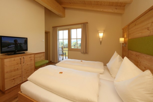 Modernes Schlafzimmer mit Flat-TV und großzügigem Balkon